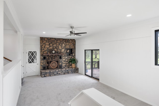 unfurnished living room with crown molding, ceiling fan, a stone fireplace, recessed lighting, and carpet floors