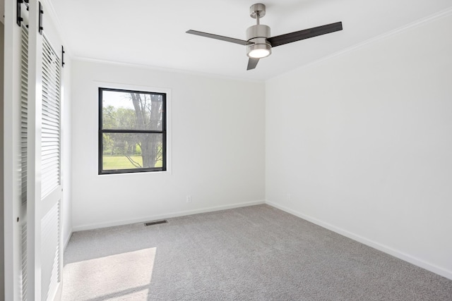 unfurnished bedroom with baseboards, a closet, carpet flooring, crown molding, and a barn door