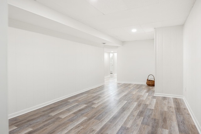 finished below grade area featuring recessed lighting, a drop ceiling, baseboards, and wood finished floors