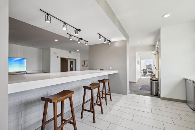 kitchen with gray cabinets, recessed lighting, rail lighting, and a breakfast bar