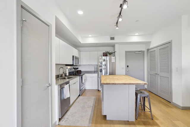 kitchen with a kitchen breakfast bar, white cabinetry, visible vents, appliances with stainless steel finishes, and butcher block countertops