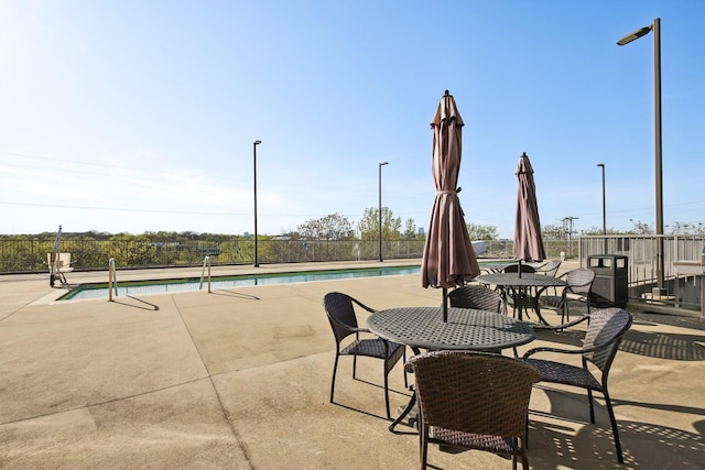 view of patio with a community pool and fence