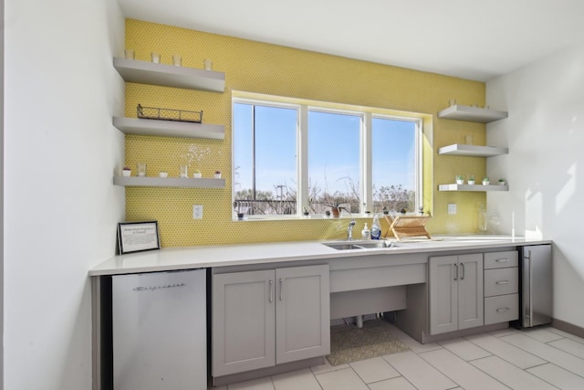 kitchen with gray cabinets, decorative backsplash, a sink, and open shelves
