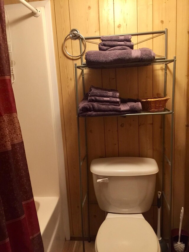 5735 Railroad St, Williston, TN 38076 - full bathroom featuring toilet, wood walls, and shower / tub combo with curtain