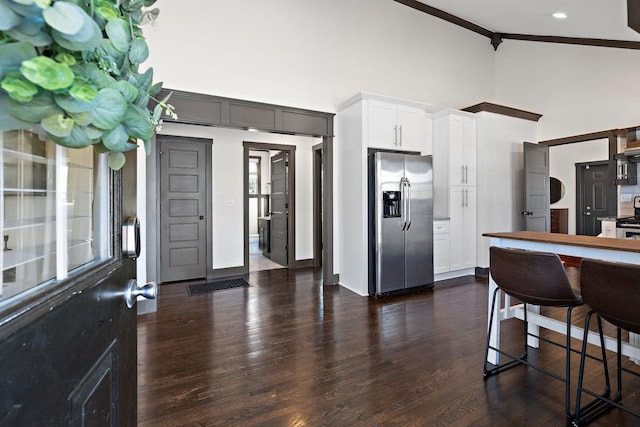 kitchen with crown molding, high vaulted ceiling, white cabinets, appliances with stainless steel finishes, and dark wood-style flooring