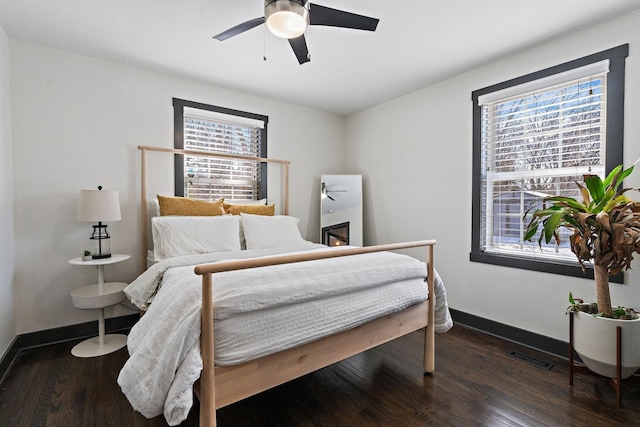 bedroom with wood finished floors, baseboards, a ceiling fan, and visible vents