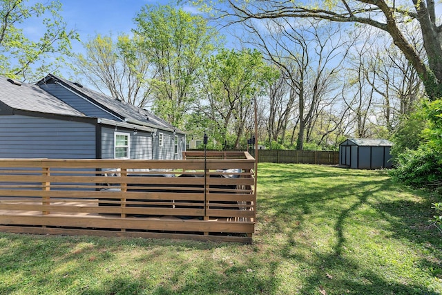 view of yard featuring a storage shed, an outbuilding, a fenced backyard, and a wooden deck
