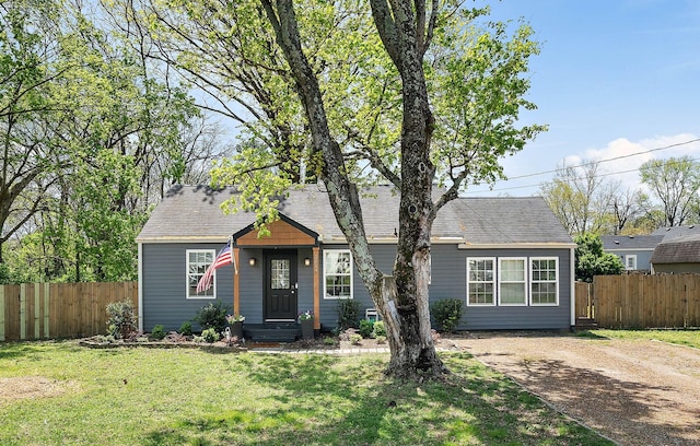 single story home with dirt driveway, a front lawn, and fence