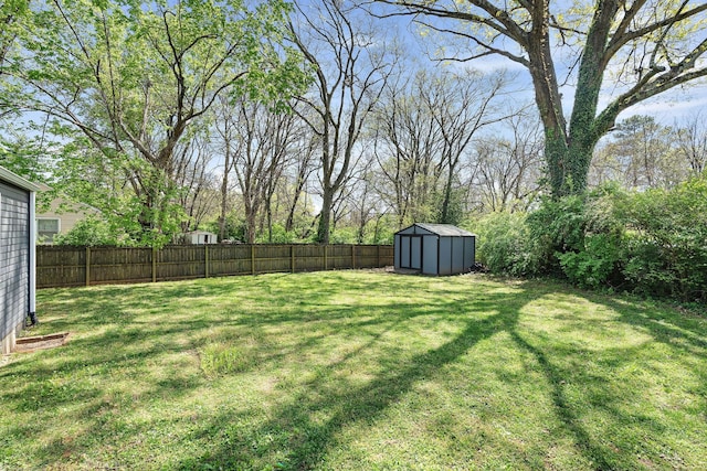 view of yard featuring a shed, a fenced backyard, and an outbuilding