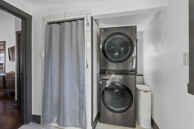 laundry area featuring stacked washer / drying machine, laundry area, and wood finished floors