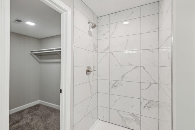 full bath featuring a walk in closet, visible vents, baseboards, and a tile shower