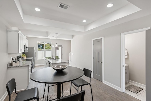 dining room featuring recessed lighting, visible vents, baseboards, and a raised ceiling