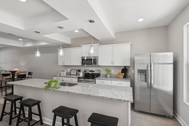 kitchen featuring stainless steel appliances, a kitchen bar, a sink, and white cabinetry