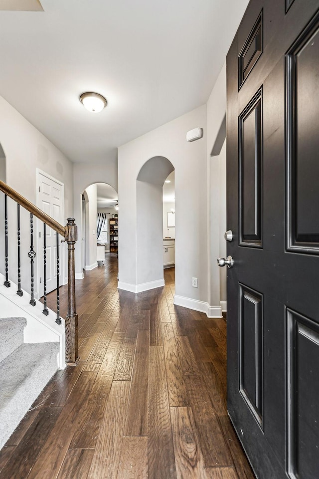 entryway with wood-type flooring, baseboards, arched walkways, and stairs