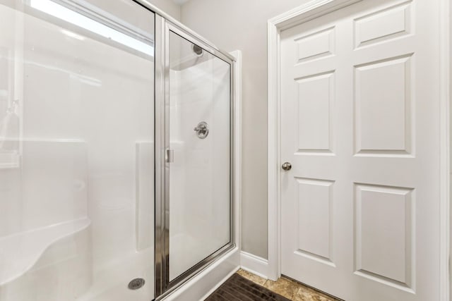 full bathroom featuring a shower stall and baseboards