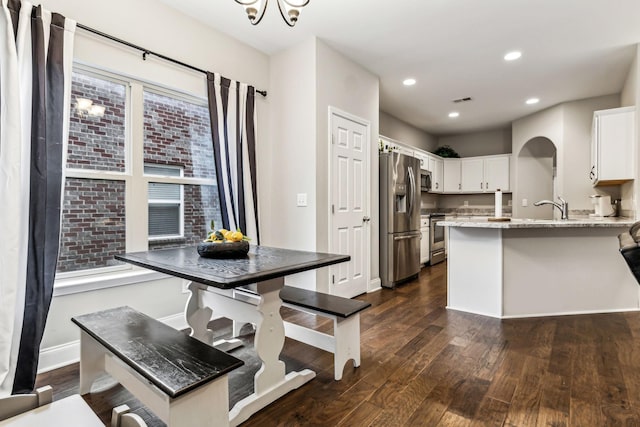 kitchen featuring a peninsula, dark wood-style floors, light stone counters, and stainless steel appliances