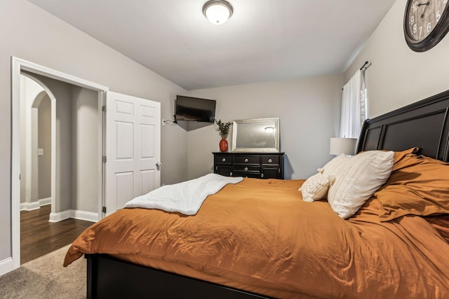 bedroom featuring arched walkways, baseboards, and dark wood finished floors