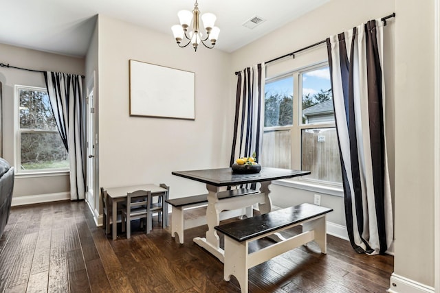 dining room with dark wood-style flooring, visible vents, baseboards, and a notable chandelier