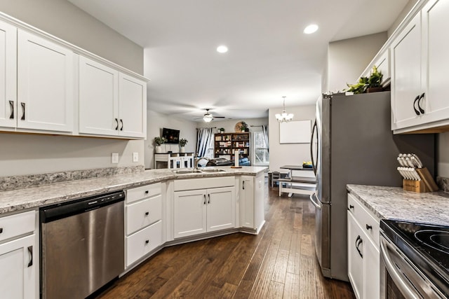 kitchen with white cabinets, dark wood-type flooring, stainless steel appliances, ceiling fan with notable chandelier, and a sink