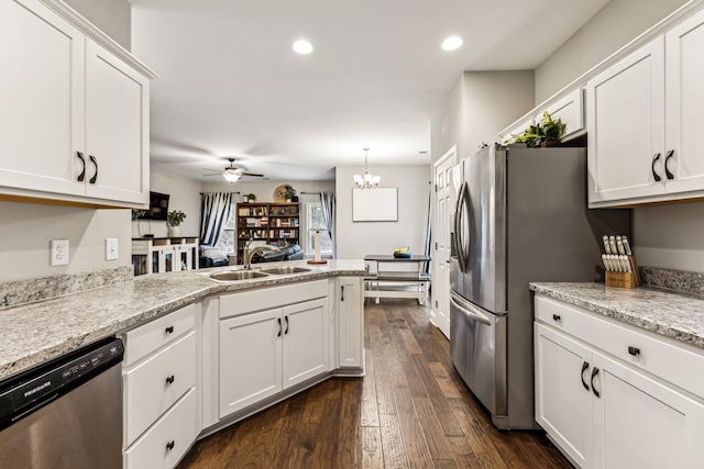 kitchen with a sink, a peninsula, white cabinetry, ceiling fan with notable chandelier, and stainless steel appliances