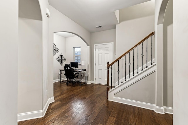 foyer entrance featuring visible vents, baseboards, arched walkways, and wood finished floors