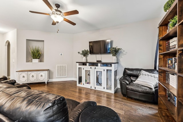 living area featuring ceiling fan, arched walkways, visible vents, wood finished floors, and baseboards