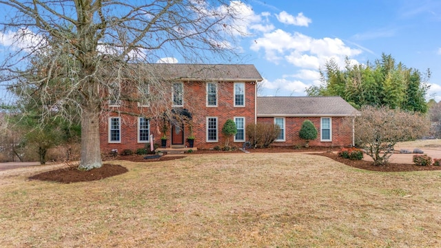 colonial inspired home featuring brick siding and a front lawn