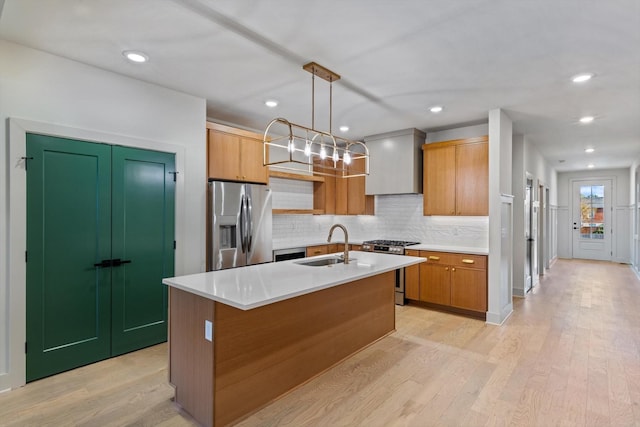 kitchen featuring tasteful backsplash, a sink, stainless steel appliances, light wood-style flooring, and premium range hood