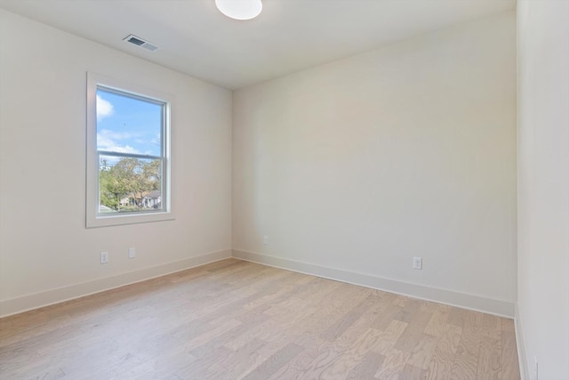 empty room featuring baseboards, light wood finished floors, and visible vents