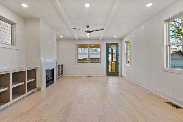 unfurnished living room featuring wood finished floors, visible vents, a ceiling fan, baseboards, and a fireplace