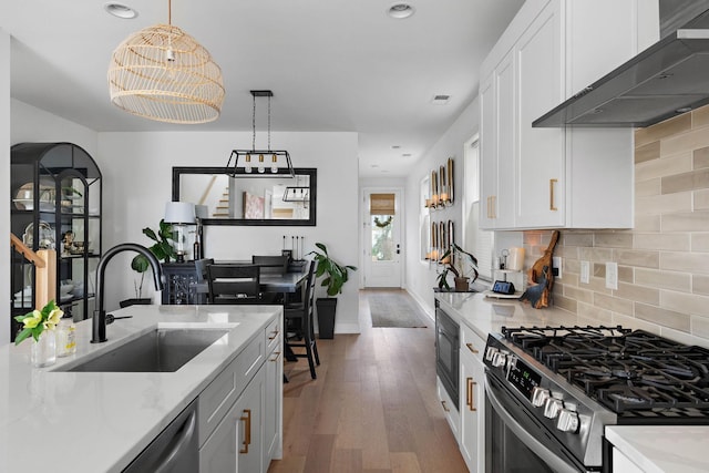 kitchen featuring a sink, white cabinets, wall chimney exhaust hood, and stainless steel appliances