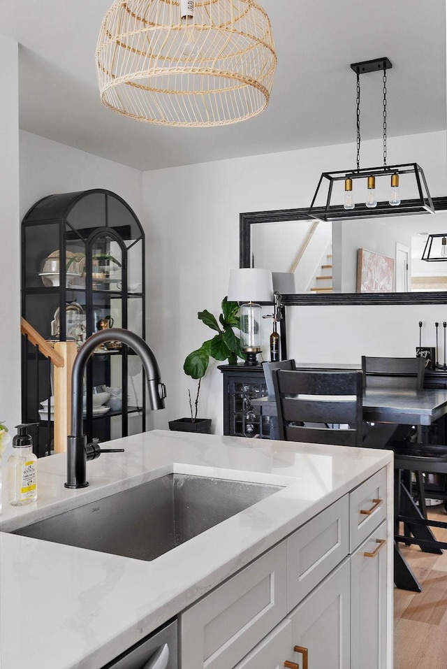 kitchen with white cabinets, light wood-style floors, pendant lighting, and a sink