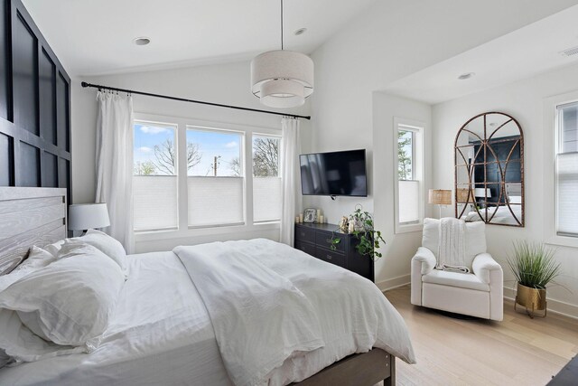 bedroom featuring visible vents, light wood-style flooring, baseboards, and lofted ceiling