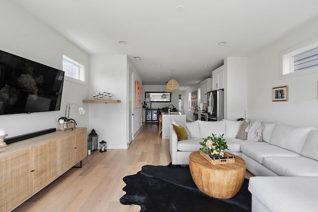 living room with baseboards, light wood-type flooring, and recessed lighting