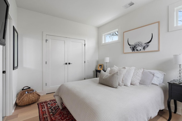 bedroom with a closet, visible vents, and light wood-type flooring