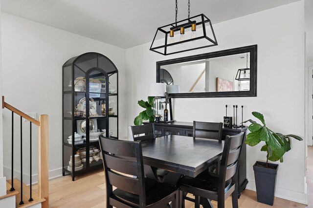 dining space with stairs, light wood-style floors, and baseboards