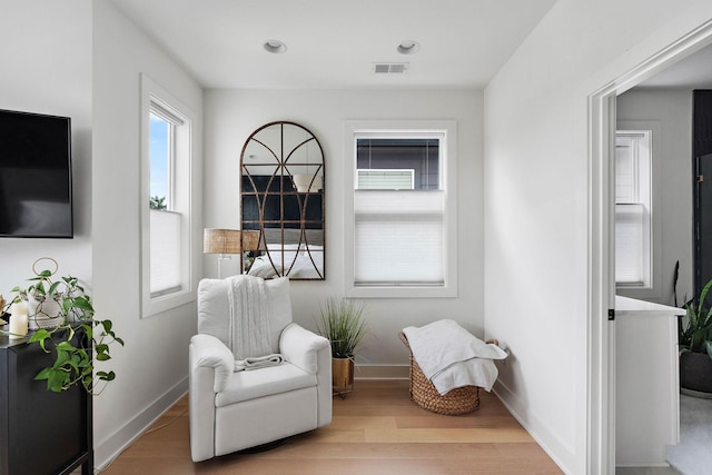 living area with visible vents, baseboards, and wood finished floors