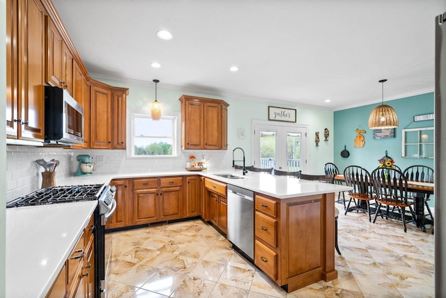 779 Iron Workers Rd W, Clarksville, TN 37043 - kitchen with stainless steel appliances, a sink, decorative backsplash, a peninsula, and brown cabinetry