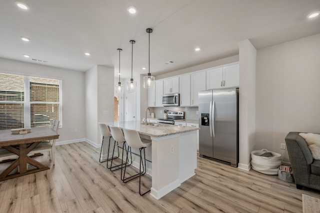 162 Jackson Alan Dr, Murfreesboro, TN 37130 - kitchen with appliances with stainless steel finishes, light wood-style floors, white cabinetry, a breakfast bar, and an island with sink