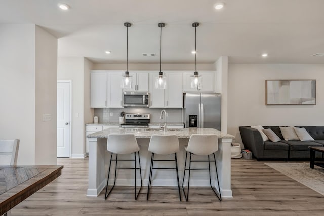 162 Jackson Alan Dr, Murfreesboro, TN 37130 - kitchen with appliances with stainless steel finishes, an island with sink, white cabinets, a kitchen bar, and recessed lighting