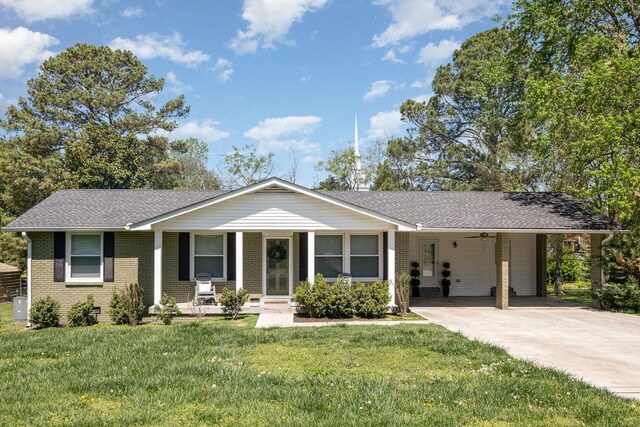 single story home with a carport, concrete driveway, a front yard, and brick siding