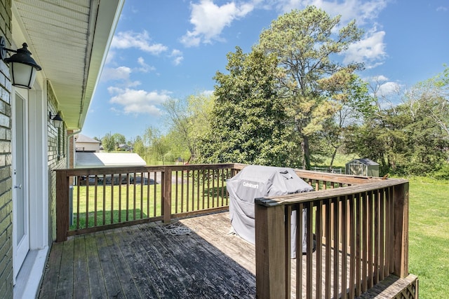 wooden terrace featuring an outbuilding, area for grilling, a lawn, and a storage unit