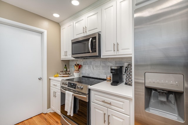 kitchen featuring white cabinets, light countertops, stainless steel appliances, light wood-style flooring, and decorative backsplash