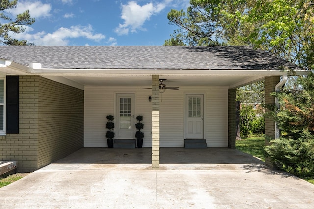view of exterior entry with a carport, driveway, a ceiling fan, and brick siding