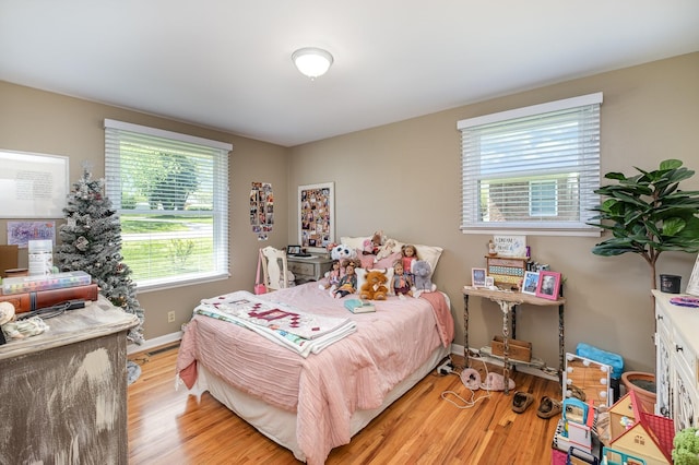 bedroom with light wood finished floors, baseboards, and multiple windows
