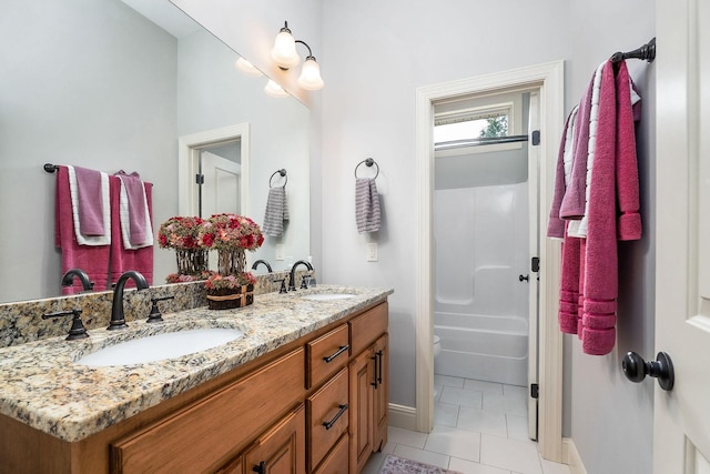 bathroom with tile patterned floors, double vanity, a sink, and baseboards