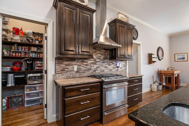 kitchen featuring dark stone countertops, gas range, decorative backsplash, and wall chimney range hood