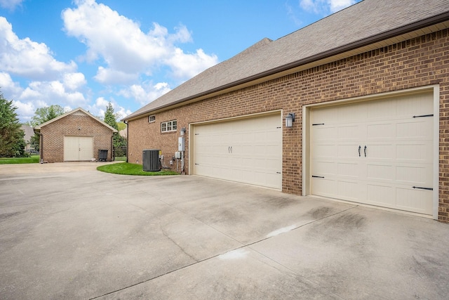 garage with concrete driveway and central AC unit