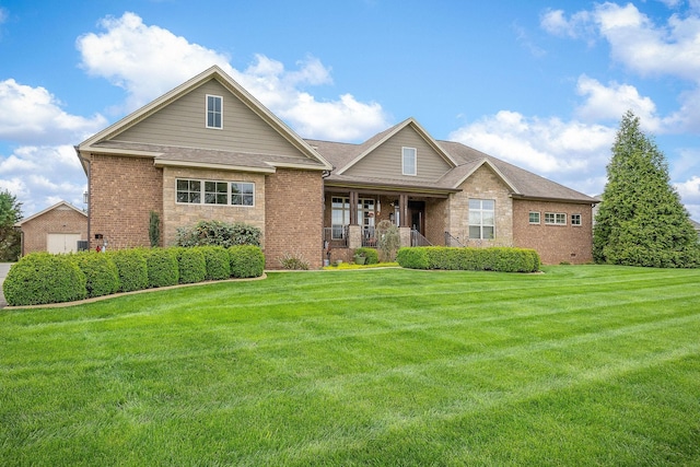 view of front of property featuring roof with shingles, brick siding, a front lawn, and covered porch