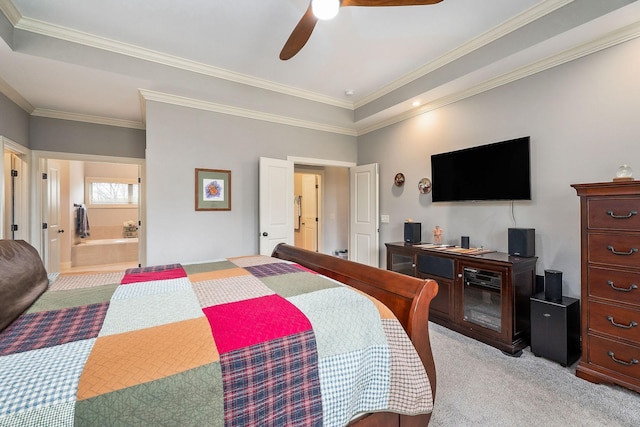 bedroom featuring ensuite bathroom, a raised ceiling, ceiling fan, crown molding, and light carpet